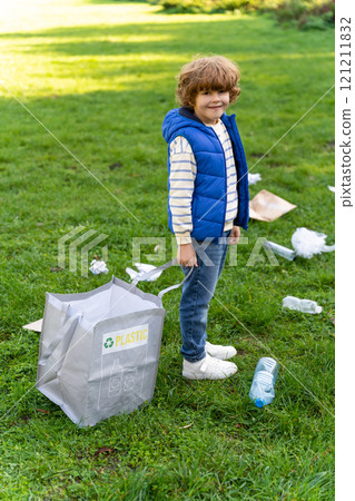 Small boy sorting garbage into recycle bags during community project 121211832