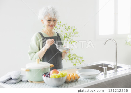 Grey-haired woman standing in the kitchen 121212236