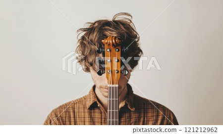 A musician stands with a fiddlehead positioned in front of their face, creating an artistic juxtaposition against a white background A musician stands with a fiddlehead positioned in front of their face, creating an artistic juxtaposition against a white background 121212962
