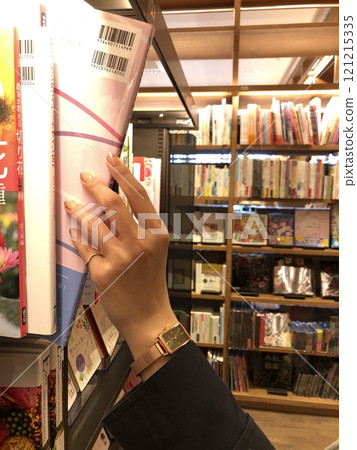 Woman's hand picking up a book in a bookstore Woman's hand picking up a book in a bookstore 121215335