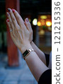 Hands of a woman praying at a shrine or temple 121215336