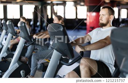 Young man exercising on exercise bike in gym 121215737
