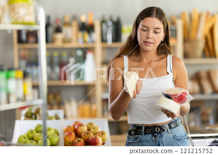Young woman choosing cheese in grocery store Young woman choosing cheese in grocery store 121215752