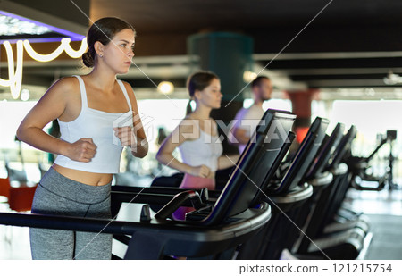 Young woman exercising on treadmill in gym Young woman exercising on treadmill in gym 121215754