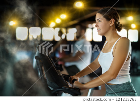 Young woman exercising on exercise bike in gym 121215765