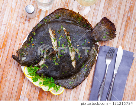 Close view of baked flounder on plate with parsley 121215784