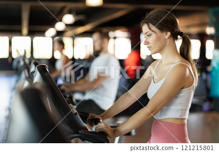 Young woman exercising on exercise bike in gym Young woman exercising on exercise bike in gym 121215801