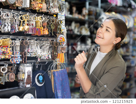 Young woman chooses keychain at souvenir market 121215925
