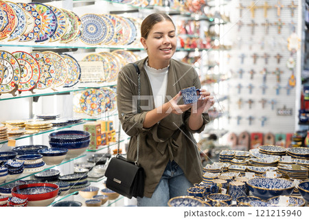 Young woman chooses souvenir dishes in souvenir shop 121215940