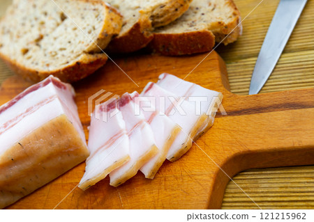 There is pound of lard and several sliced slices on cutting board. 121215962