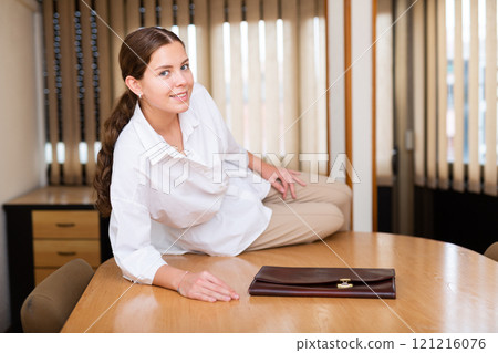 Attractive woman with briefcase sitting on table in meeting room 121216076
