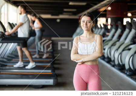 Young woman posing by treadmill in gym 121216123