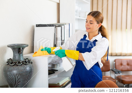 Professional female worker of office cleaning service wiping furniture Professional female worker of office cleaning service wiping furniture 121216356