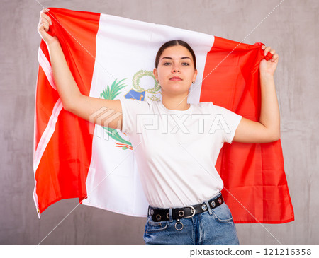 Calm cheerleader girl holds Peru flag in her hands. Isolated on gray background Calm cheerleader girl holds Peru flag in her hands. Isolated on gray background 121216358
