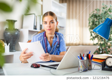 Young woman therapist working with case histories on laptop in office 121216476
