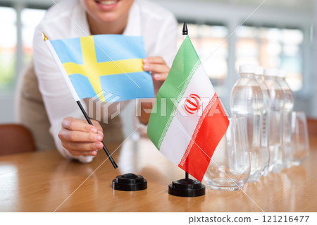Employee of delegation prepares negotiating table - sets up flag of Iran and Sweden 121216477