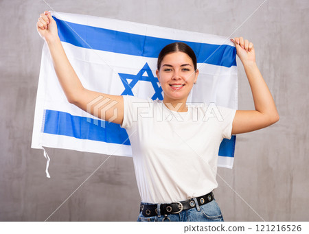 Happy girl stands with flag of Israel. Isolated on gray background Happy girl stands with flag of Israel. Isolated on gray background 121216526