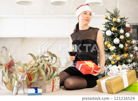 girl holds box with gift and glass of wine. She dreams of new year holiday. 121216529