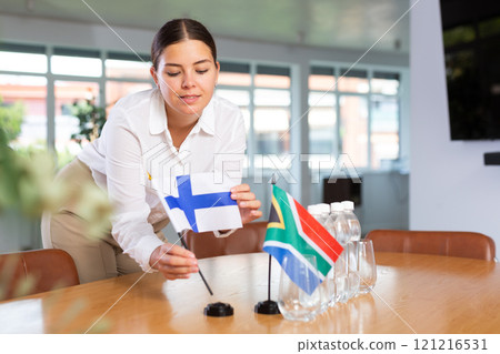 Young lady sets miniatures flags of South Africa and Finland for international negotiations 121216531