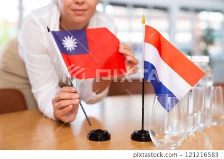 Blurry girl set midget flags of Netherlands and Taiwan before international negotiations 121216583