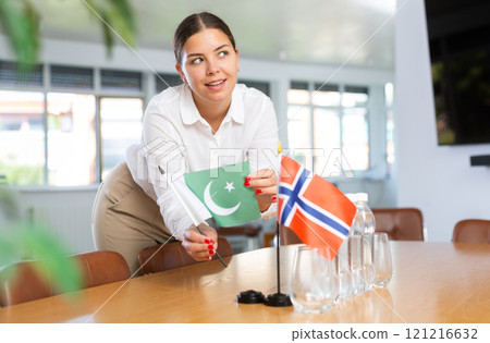 Young lady sets miniatures flags of Norway and Pakistan for international negotiations 121216632
