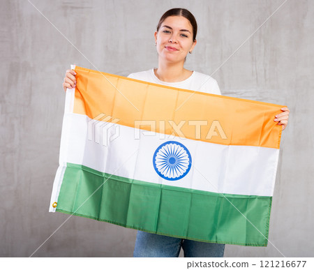 Joyful smiling young woman waving flag of India against gray wall background Joyful smiling young woman waving flag of India against gray wall background 121216677