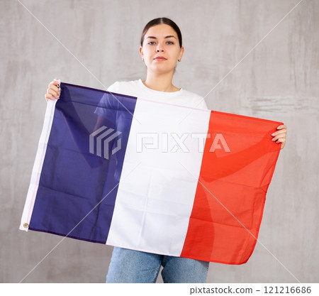 Calm cheerleader girl holds France flag in her hands. Isolated on gray background 121216686
