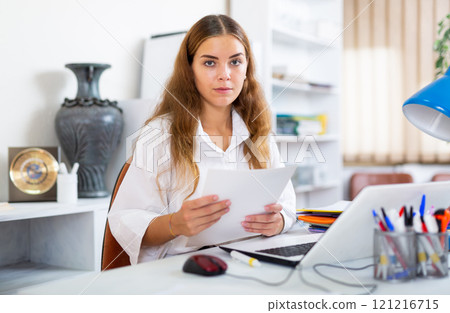 Female clerical worker sitting at desk in office Female clerical worker sitting at desk in office 121216715