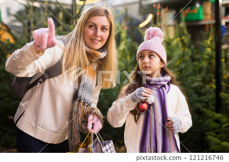 Family of mother and teen daughter having fun on outdoor fair, choosing fir tree for New Year celebration 121216746