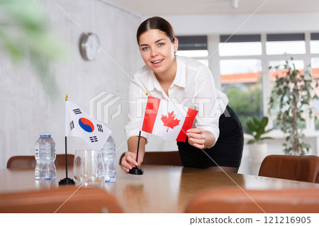 Businesswoman arranging flags of South Korea and Canada for presentation and negotiations in room Businesswoman arranging flags of South Korea and Canada for presentation and negotiations in room 121216905