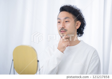 中年男子一邊照鏡子一邊護理自己的皮膚 121217858