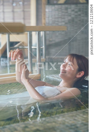 A young woman relaxing in an open-air bath. Photo courtesy of Shiratama no Yu Izumi Kei 121218604