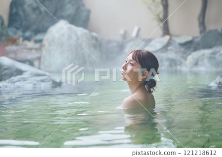 一位年輕女子在露天浴池中放鬆 攝影由 Izukei Shiratama-no-yu 提供。 121218612
