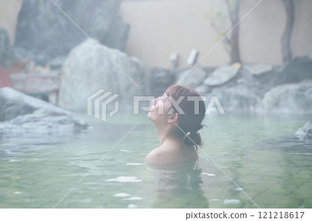 一位年輕女子在露天浴池中放鬆 攝影由 Izukei Shiratama-no-yu 提供。 一位年輕女子在露天浴池中放鬆 攝影由 Izukei Shiratama-no-yu 提供。 121218617