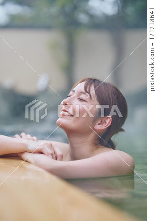 一位年輕女子在露天浴池中放鬆 攝影由 Izukei Shiratama-no-yu 提供。 121218641