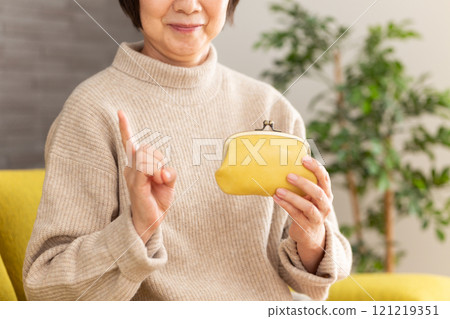 穿著冬衣的中高級女性拿著錢包微笑 穿著冬衣的中高級女性拿著錢包微笑 121219351