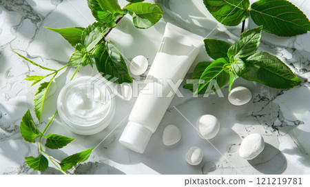 White tube of cosmetic cream on a marble surface, next to green leaves and light stones White tube of cosmetic cream on a marble surface, next to green leaves and light stones 121219781