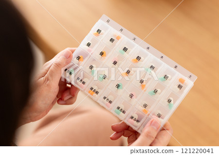 Middle-aged to senior women holding regular medications in a pill case 121220041