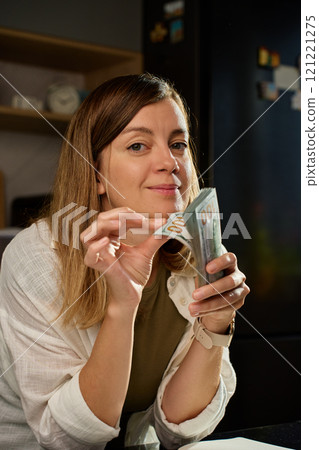 Woman counting stack of dollar bills at home Woman counting stack of dollar bills at home 121221275