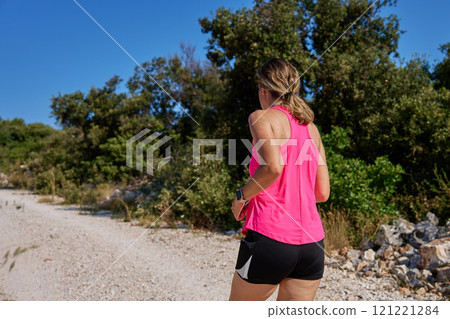 Woman running on rocky trail on sunny day 121221284