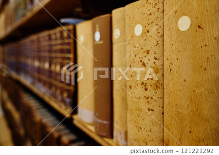 Old books on wooden shelves in library 121221292