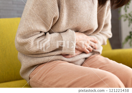 Middle-aged to senior woman suffering from stomach pain in winter room Middle-aged to senior woman suffering from stomach pain in winter room 121221438