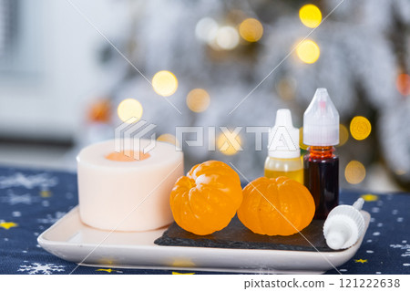 Handmade soap in the form of Orange tangerine with bottles of dye, flavor, a block of glycerin soap base, silicone mold, on background of Christmas tree with golden light. Soap as gift new year Handmade soap in the form of Orange tangerine with bottles of dye, flavor, a block of glycerin soap base, silicone mold, on background of Christmas tree with golden light. Soap as gift new year 121222638