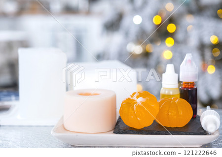 Handmade soap in the form of Orange tangerine  with bottles of dye, flavor, a block of glycerin soap base, silicone mold, on background of Christmas tree with golden light. Soap as gift new year 121222646