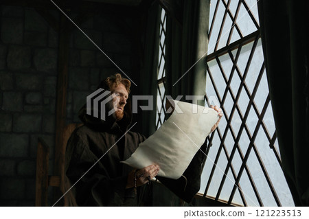 Medieval monk reading obsolete historical parchments and holy manuscripts 121223513