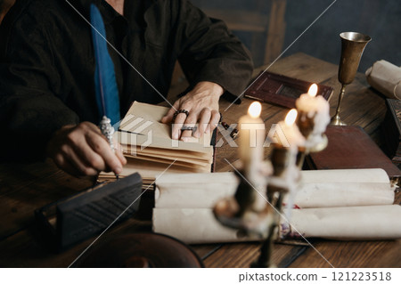 Medieval monk writing historic manuscripts at table 121223518