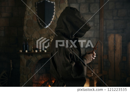 Faithful priest in robe hood praying with rosary beads and cross 121223535
