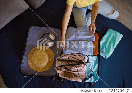 Unrecognizable woman traveler packing luggage preparing for summer vacation 121223647