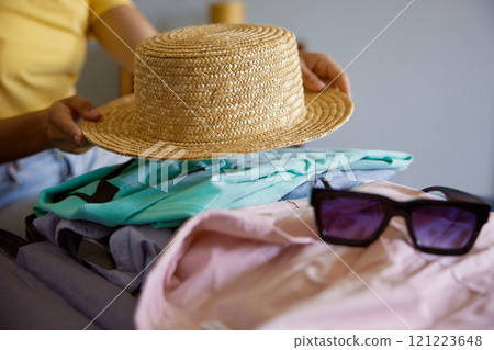 Unrecognizable woman traveler packing luggage preparing for summer vacation Unrecognizable woman traveler packing luggage preparing for summer vacation 121223648