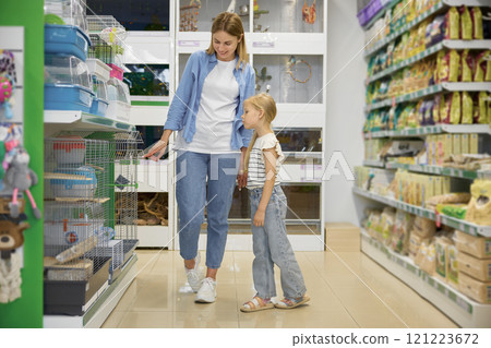 Happy mother and daughter walking through rack of pet shop Happy mother and daughter walking through rack of pet shop 121223672